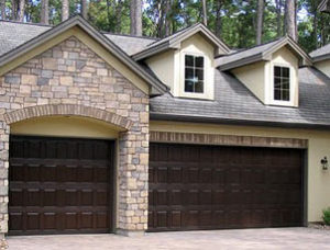 Three-car dark woodgrain paneled garage doors on a home.